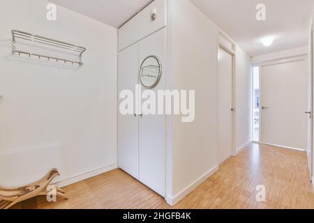 Light narrow hallway with many doors in white walls and mirror Stock Photo