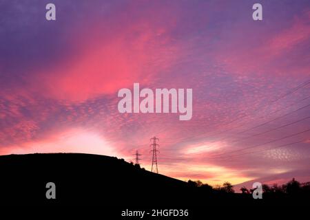 Hewenden, West Yorkshire: Dramatic sunset in West Yorkshire countryside where power lines stand out against the evening sky. Stock Photo