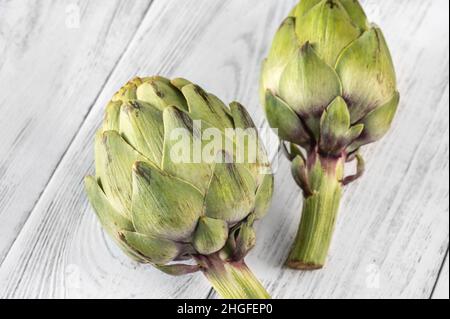 Two uncooked artichokes on the wooden table Stock Photo