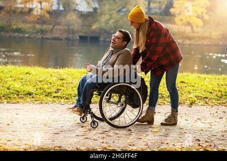 Woman and her friend in a wheelchair having stroll through the town ...