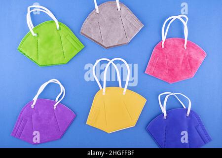 The Concept of Shopping during the pandemic Covid lockdown. Blue, Black, Red, yellow and green respirator protective masks on blue paper bg. Stock Photo