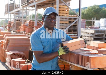 man is checking quality of bricks in the open area of a construction store Stock Photo
