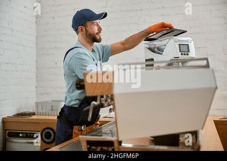 Smiling man repairing coffee machine in cafe Stock Photo