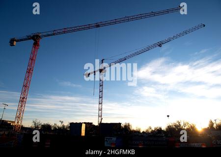Construction cranes tower over an apartment construction site in downtown Colorado Springs, Colorado Stock Photo