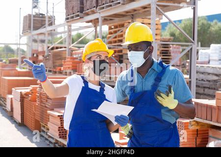 Two workers in masks keep track of the number of redbricks Stock Photo