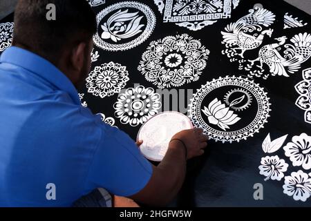 Indian Seller Man making rangoli from design patterns of Rangoli with circles. These beautiful designs are made in every hindu home to decorate and ce Stock Photo