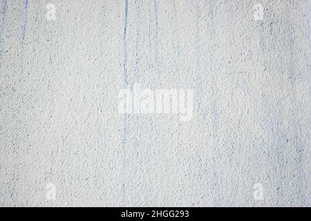 Painted light rough wall with stains of blue paint. Stock Photo