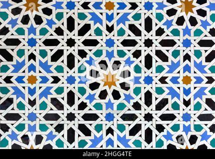 Old Islamic tiles (also known as zellige or azulejos) with traditional geometric patterns decorating a wall of the Nasrid Palaces inside the Alhambra. Stock Photo