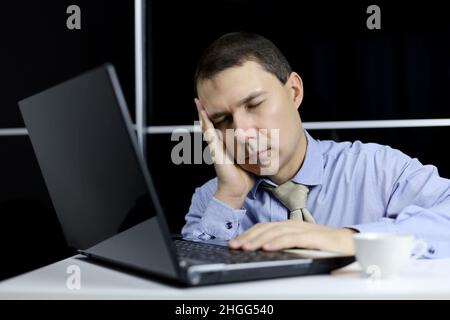 Man in the sleeping at laptop. Office worker after sleepless night, tired of overworking concept, chronic fatigue at workplace Stock Photo