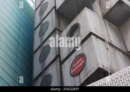 Detail of Nakagin Capsule Tower in Tokyo. Sign in a window reads '#Save Nagakin'. The under-demolition Nagakin Shiroyama Building is next to it behind Stock Photo