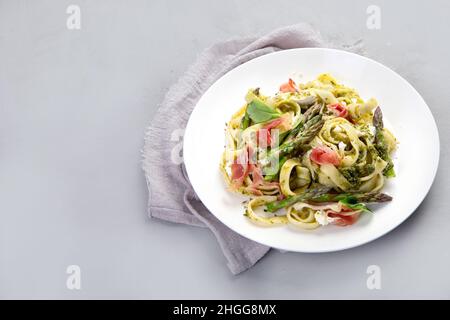 Pasta with asparagus and prosciutto on gray background. Traditional Italian Food concept. Top view, flat lay Stock Photo