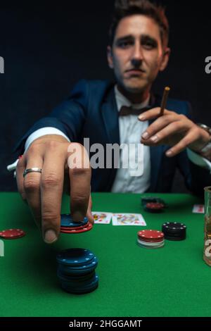 Poker player with cards and chips at green table in casino. Stock Photo