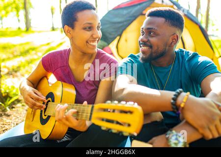 latin hispanic couple in love together in great sunny day in park with guitar and tent Stock Photo
