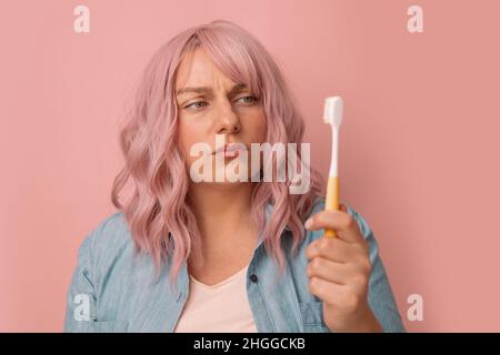 Portrait of young woman with aching teeth, pain in sensitive bleeding gums, brushing teeth. Dental care Stock Photo