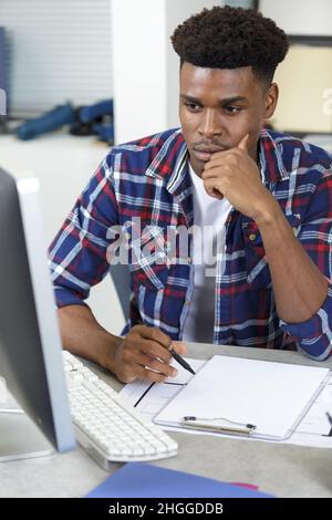 man deep in thought sat at computer desk Stock Photo