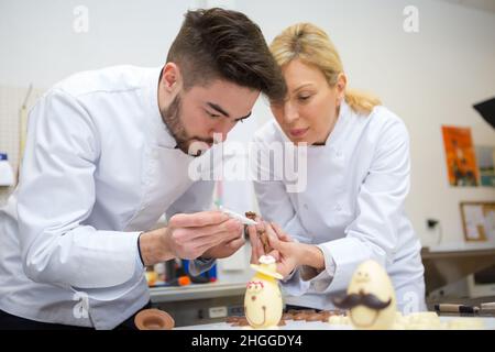 young chocolatier making topping designs on the chocolates Stock Photo