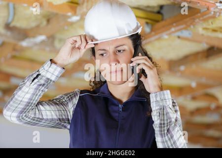 young woman builder confused on the phone Stock Photo