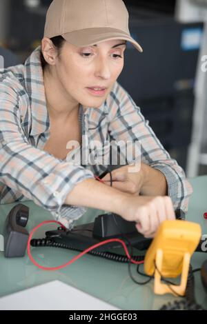 female electrician using multimeter to check telephone voltage Stock Photo