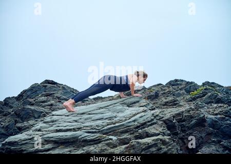 A Native American woman from Spain practicing yoga at the beach on a gloomy day Stock Photo