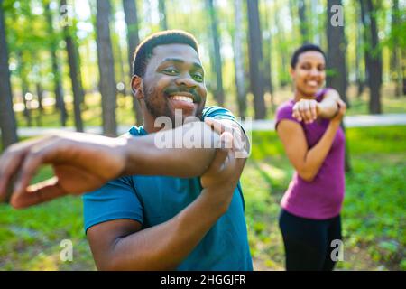 Young man and beautiful woman doing stretching exercises outdoors Stock Photo