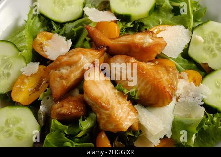 Fresh Salad with grilled cubes of teriyaki Salmon, cheese chunks on bed of spring mix lettuce with cucumber and tomatoes Stock Photo