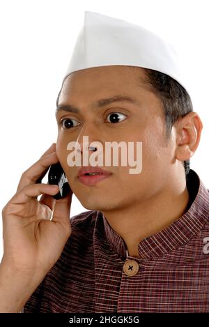 Mumbai; Maharashtra; India- Asia; Dec. 26; 2009 - Portrait of young handsome smiling Indian politician talking on mobile phone white background Stock Photo