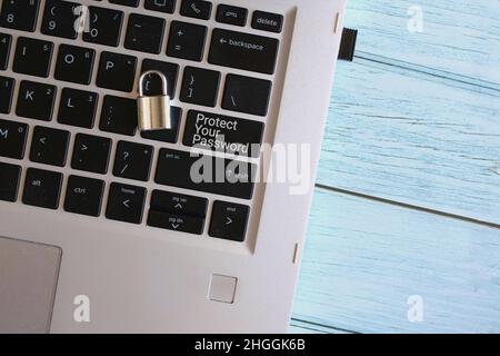 Technology and security concept. Top view image of padlock and laptop with text PROTECT YOUR PASSWORD. Stock Photo