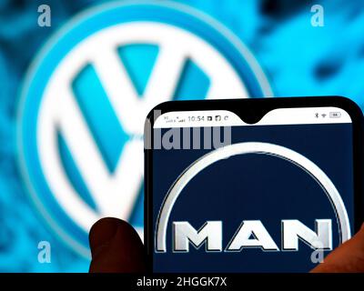 In this photo illustration, the MAN Truck & Bus SE logo is seen displayed on a smartphone screen with the Volkswagen AG logo in the background. Stock Photo