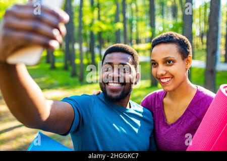 latin american couple ready to yoga time outdoors pink and blue look taking self portrait on modern smartphone Stock Photo