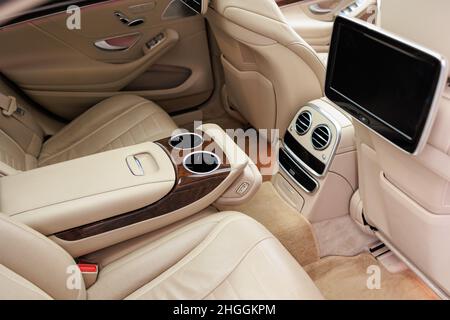 The rear seats of the luxury car in real wood and leather and the multimedia screen Stock Photo