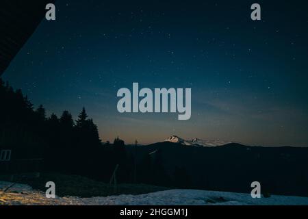 Snowy meadow, snowy mountains and stars in the background Stock Photo