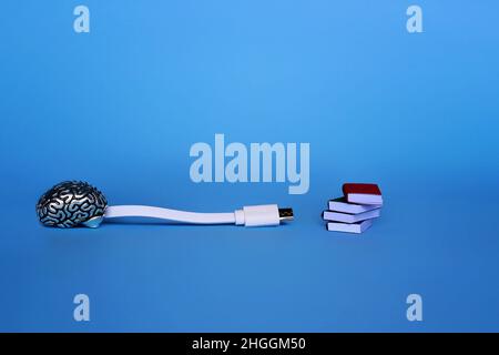 Study, learning, knowledge transfer concept. White cable, brain model and pile of books on blue background. Stock Photo