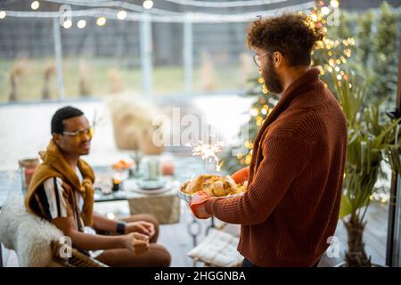 Two male friends having festive dinner at backyard Stock Photo
