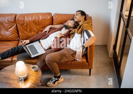 Male gay couple talking on a couch at home Stock Photo