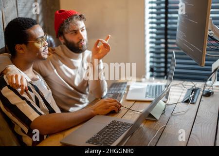 Gay couple working on computers at home office Stock Photo