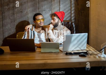 Gay couple working on computers at home office Stock Photo
