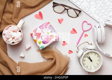 Desktop. Valentine's day gift marshmallow keyboard glasses scarf headphones alarm clock on gray table. Flat lay copy space Stock Photo