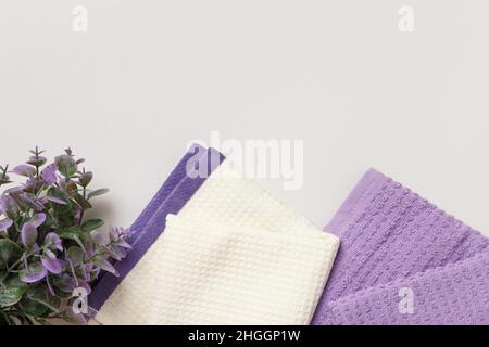 White and purple waffle towels and a flower plant on a gray background. Stock Photo