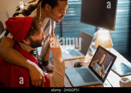Stylish gay couple having video call with female colleague Stock Photo
