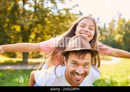 Father having fun piggybacking his daughter in summer in nature Stock Photo