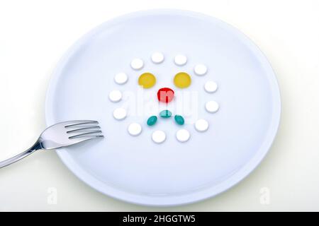 plate with pills in the shape of a face, symbolic image for synthetic food, tablet consumption, tablet abuse Stock Photo