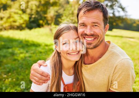 Proud and happy father hugs his daughter in park in summer in nature Stock Photo