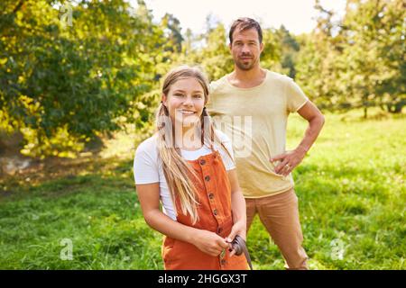 Happy daughter and father standing happily together in summer in park in nature Stock Photo