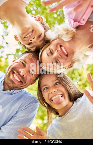 Girl cheekily sticks out tongue and fools around with brother and parents Stock Photo