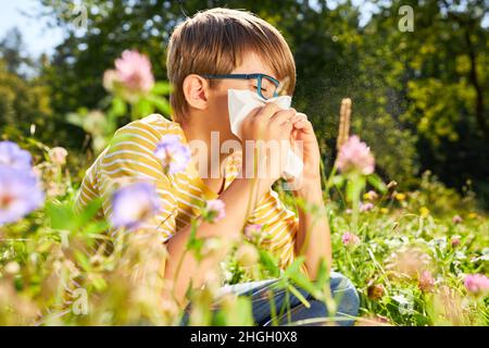 Child with hay fever sneezes into handkerchief on meadow in summer Stock Photo