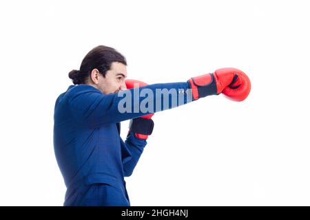 Angry businessman with red boxing gloves, punching with hand, fighting position, clenching teeth. Side view portrait of determined business person kic Stock Photo