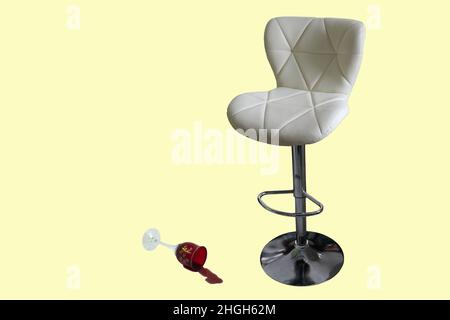 Bar stool and wine glasses on a light background. There is a glass of spilled wine by the chair. Stock Photo