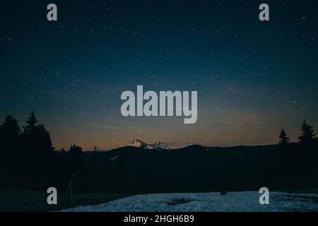 Snowy meadow, snowy mountains and stars in the background Stock Photo