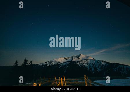 Snowy meadow, snowy mountains and stars in the background Stock Photo