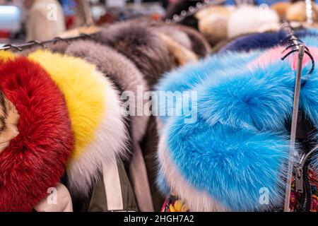 Fur coats in a row on a hanger in the store. Female fashion, natural mink fur clothes of different colors Stock Photo